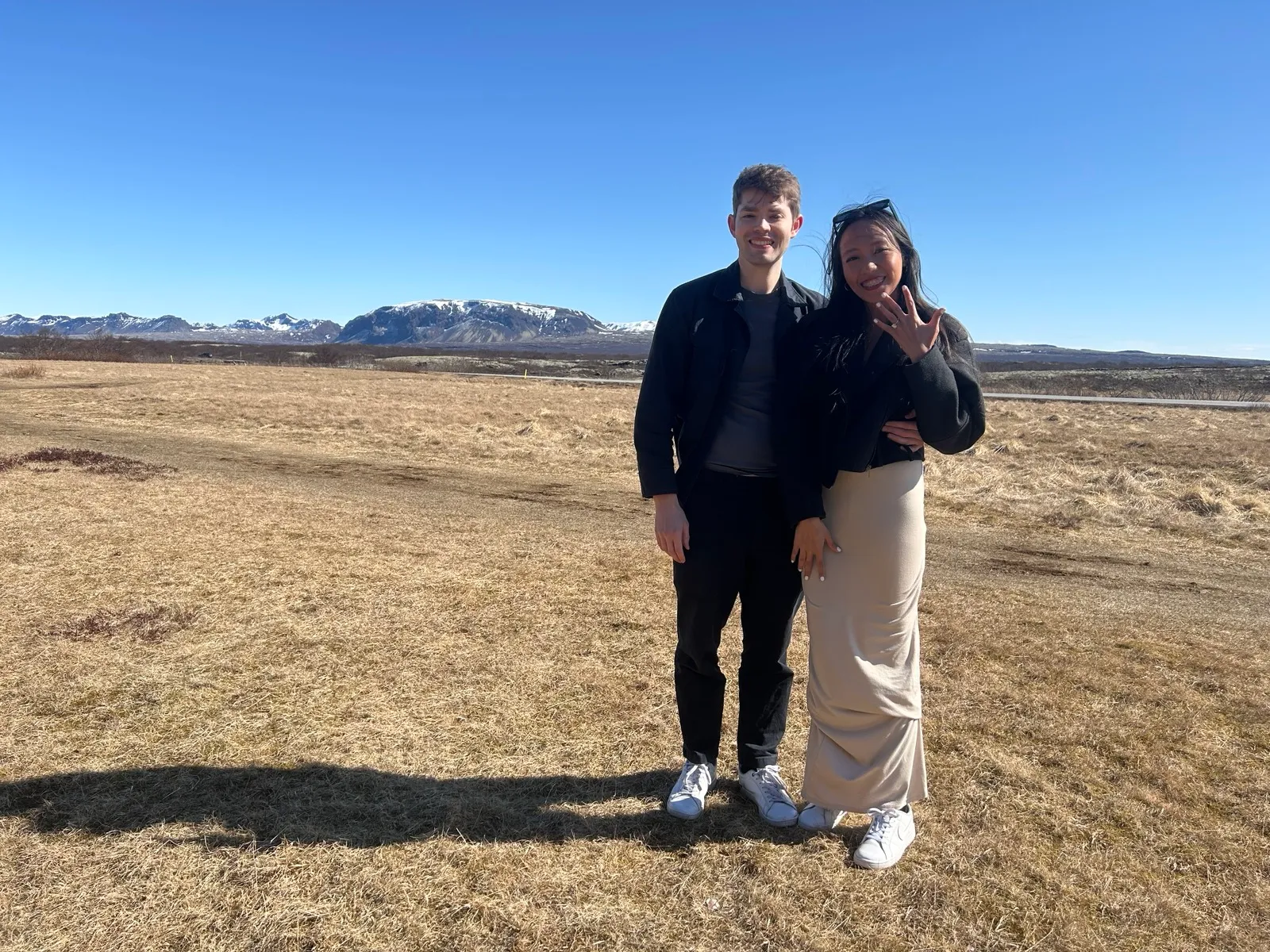 Cherika and Chris in Iceland, just engaged, with snow-capped mountains behind them